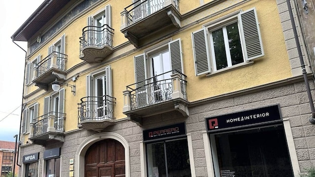 Ein mehrstöckiges Gebäude mit einer gelben Fassade, einer großen Holztür und einer Schaufensterfront mit der Aufschrift "HOME & INTERIOR".