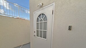 Una puerta blanca con un ventanal de vidrio esmerilado, un picaporte metálico y un enchufe en la pared.