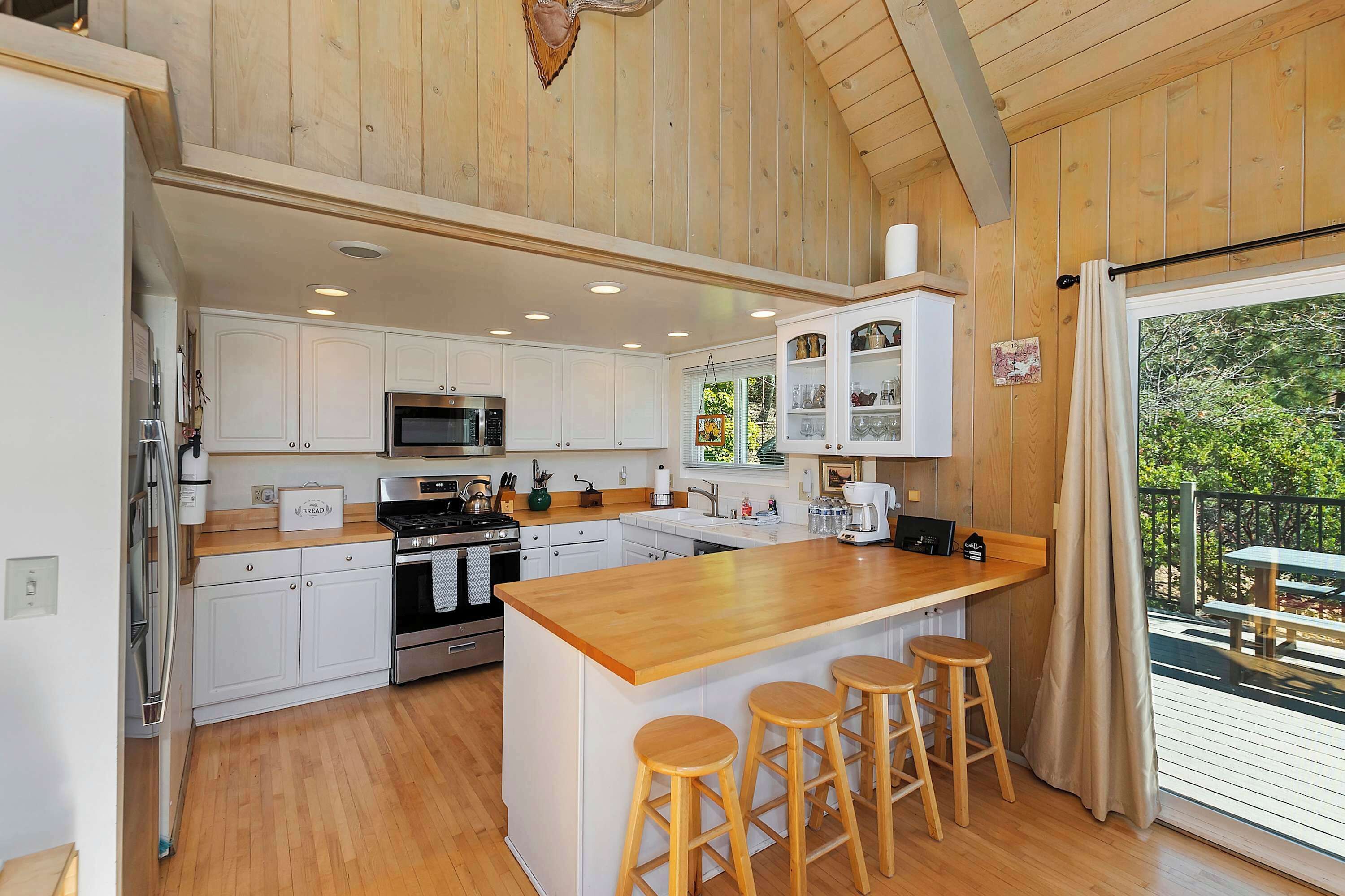 Una cocina amplia con armarios de madera, una isla central con taburetes y vistas al exterior.