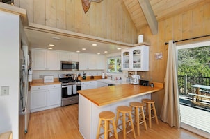 A spacious kitchen with wooden cabinets, a central island with stools, and a view of the outdoors.
