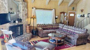 A cozy living room with a stone fireplace, leather furniture, and a wooden ceiling.