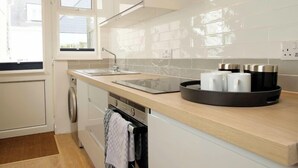 A modern kitchen with white cabinets, a sink, a stove, and a window.