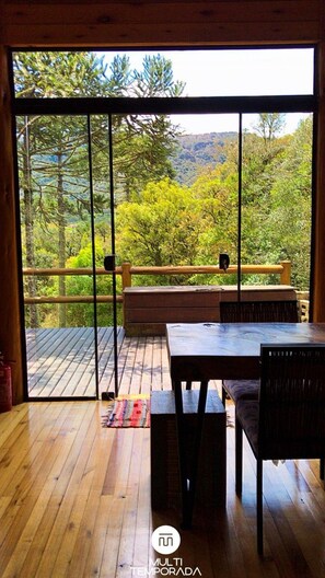 Una terraza de madera con una mesa y sillas, con vista a una zona boscosa.