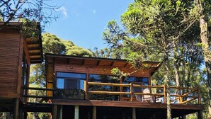 A wooden cabin with a balcony, surrounded by trees and grass. - Cabana Fruta Fina - Urubici - SC (Urubici)