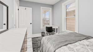 A bedroom with a bed, a desk, and a chair. There is a door with the number 2 on it.