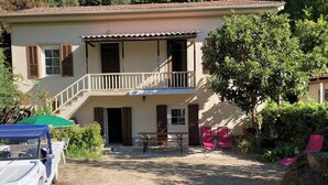 Una casa de dos pisos amb un balcó, una taula i dues cadires al jardí davanter.