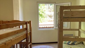 Una habitació de dormitori amb dos llits superposats, una finestra i una porta.