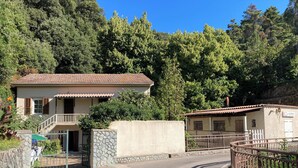 Un edifici de dues plantes amb teulada de rajola, mur de pedra i entrada tancada per una reixa.