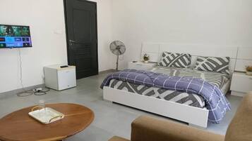 Una camera da letto con un letto, una scrivania, una sedia, una TV e una ventola.