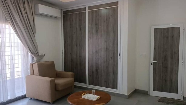 A room with a beige sofa, a round wooden coffee table, and a large wardrobe with a sliding door.