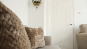 Une pièce avec une porte blanche, un fauteuil beige et un canapé à la texture intéressante.