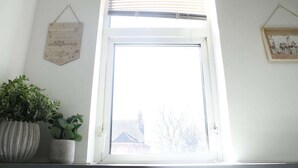 Une pièce avec une fenêtre, une plante en pot et un panneau fixé au mur.