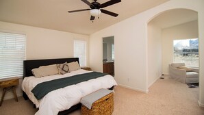 A bedroom with a bed, a ceiling fan, a window, and a view of the outdoors.