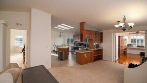A spacious living area with a kitchen, dining area, and a view of the outdoors.