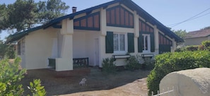 A two-story house with a front porch, a small garden, and a dog.