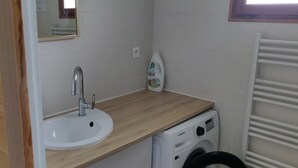 A compact bathroom with a wooden countertop, a white sink, a washing machine, and a radiator. - Family home for 10 people, 600 m from the ocean – large garden (Mimizan)