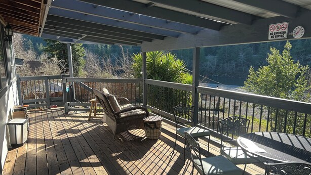 Une terrasse en bois, aménagée avec du mobilier d’extérieur, notamment des chaises et une table, et offrant une vue sur un paysage naturel.