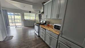 Une cuisine moderne avec des meubles gris, un plan de travail en bois et un four à micro-ondes encastré.