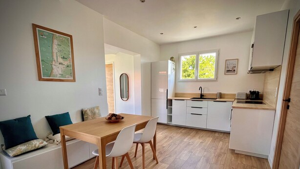 A modern kitchen with white cabinets, a wooden dining table, and a built-in oven.