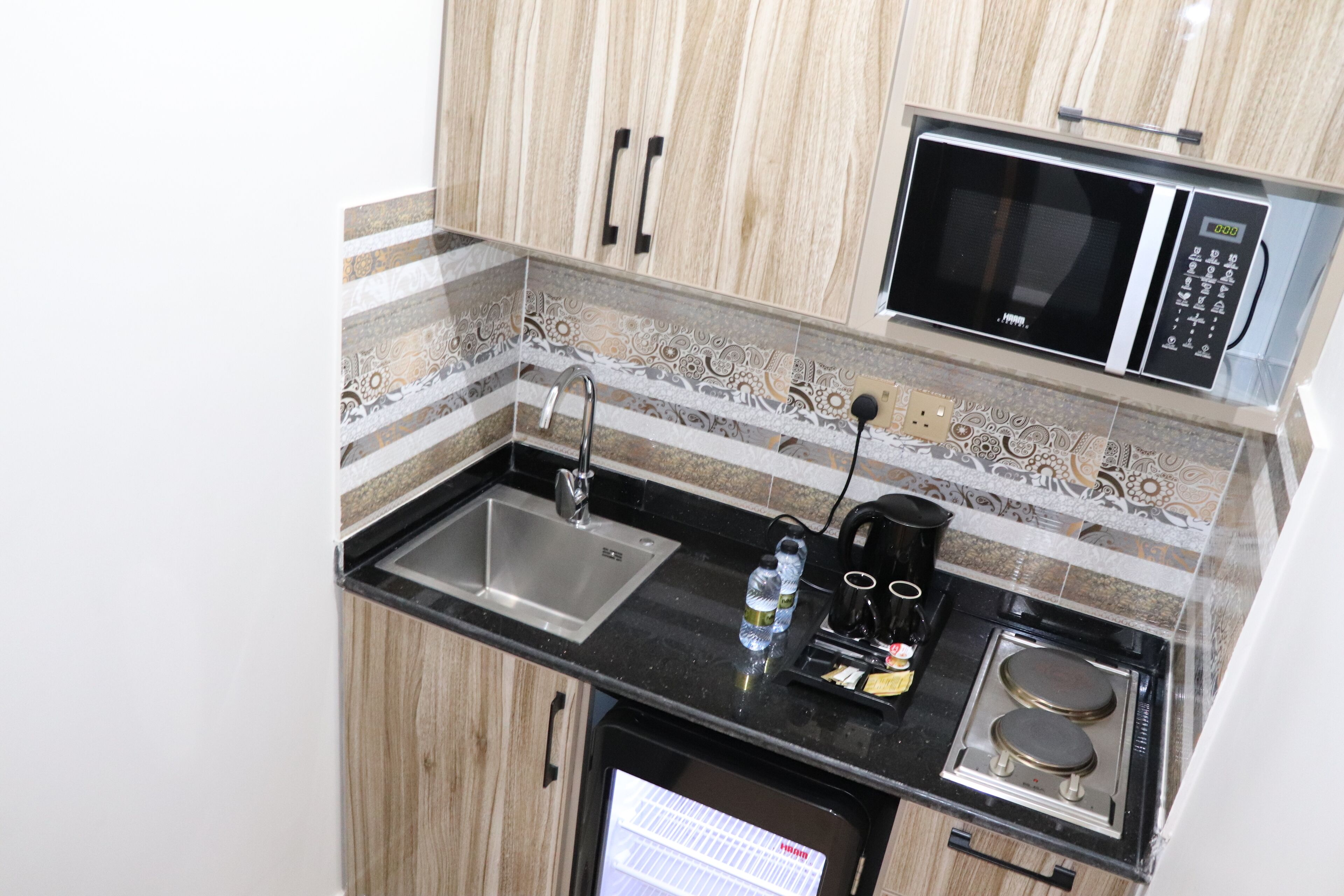 A compact kitchen with a sink, a microwave, a coffee maker, and a small refrigerator.