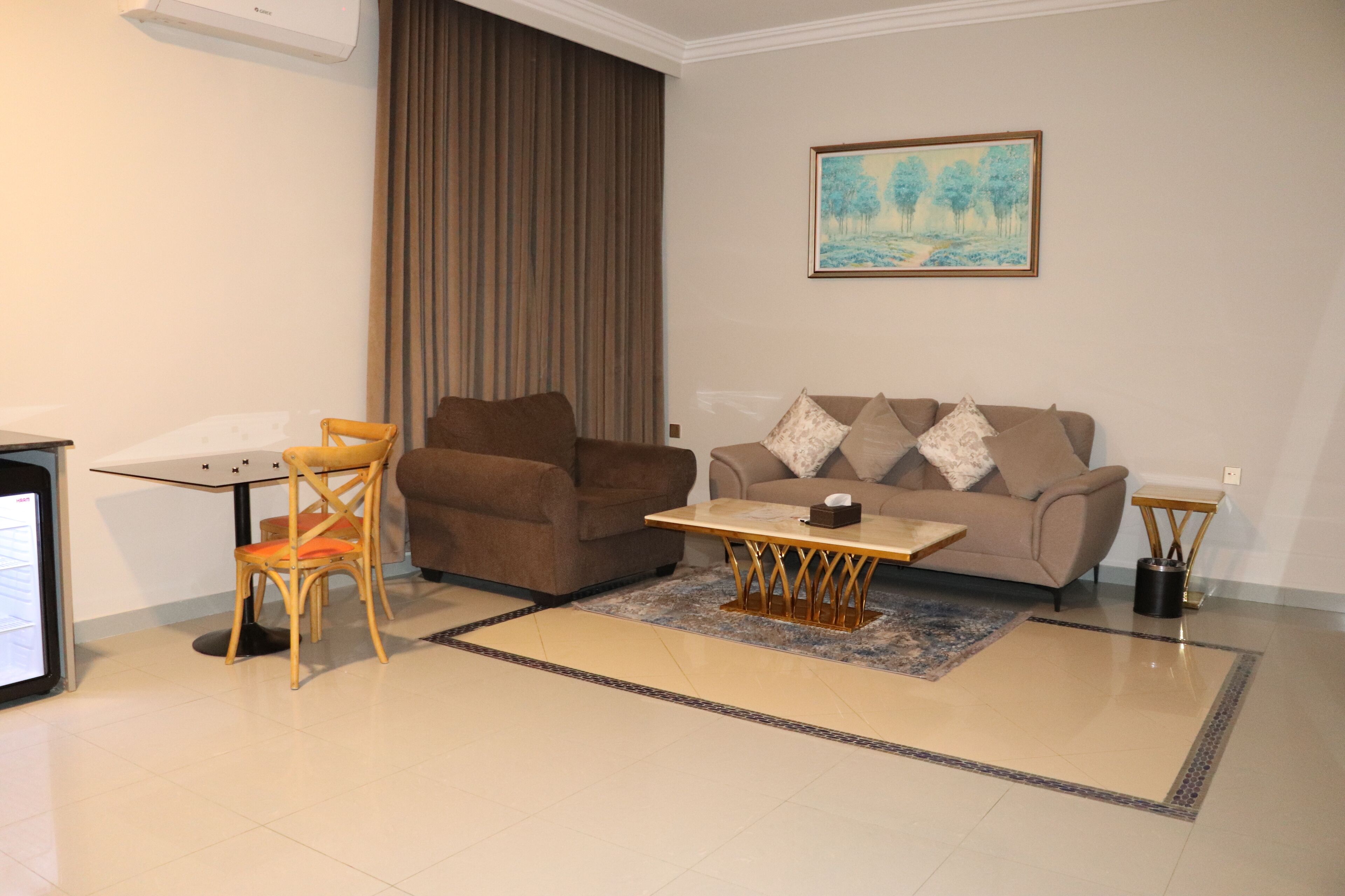 A living room with a brown sofa, a wooden chair, a small table, and a painting on the wall.