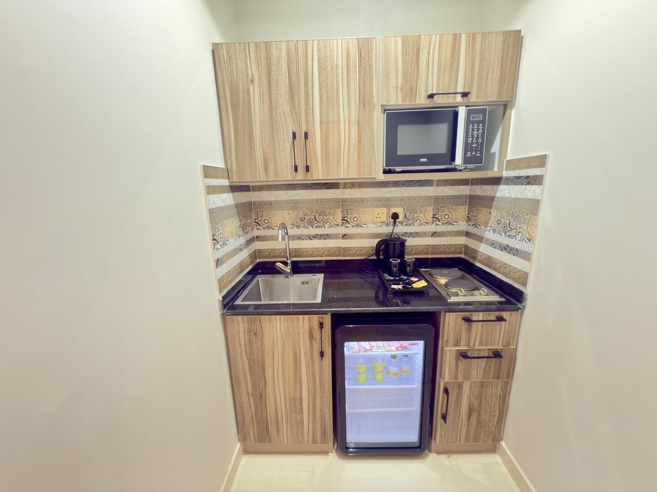 A compact kitchen with a built-in microwave, a small refrigerator, and a sink.