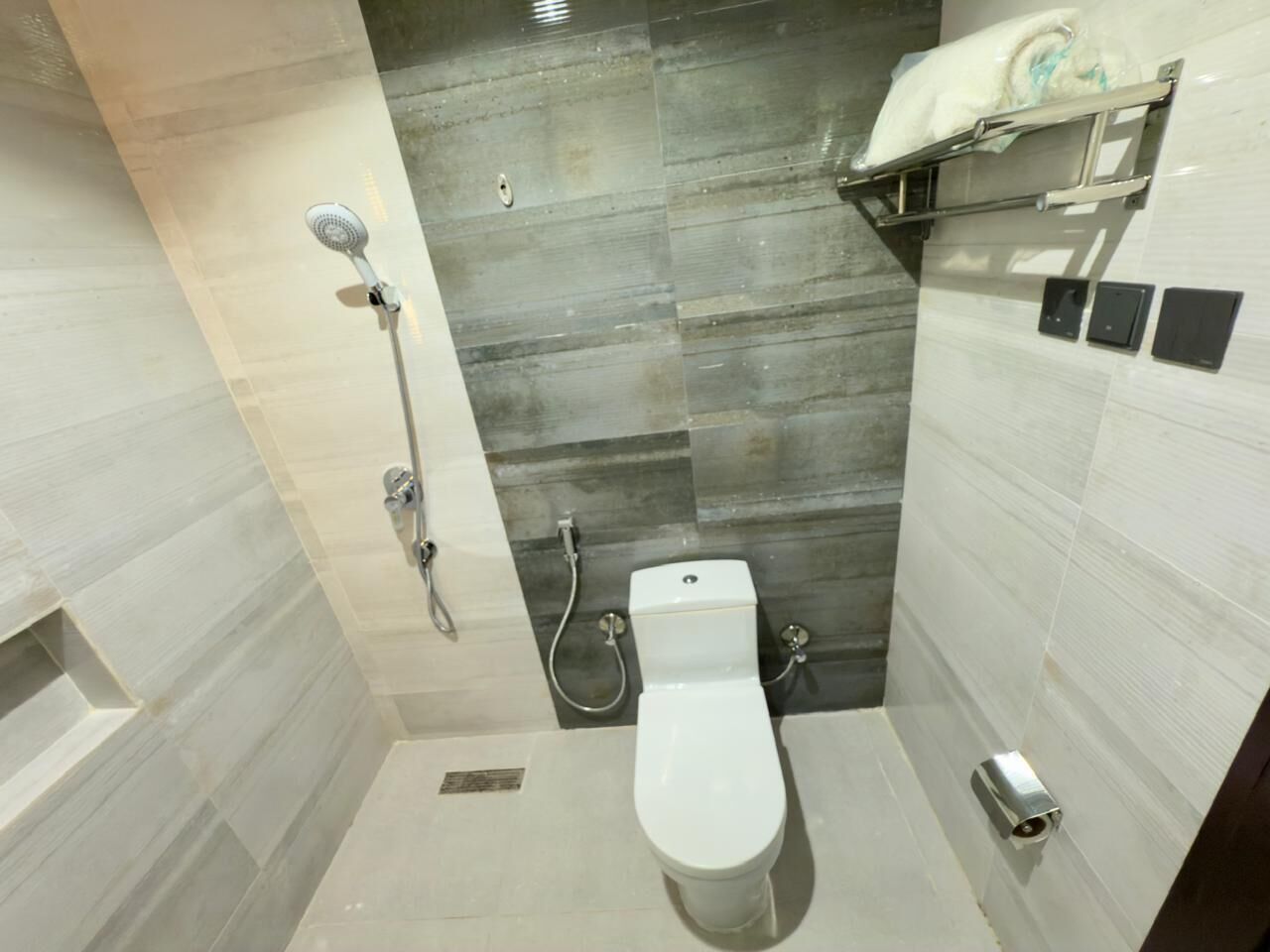 A modern bathroom with a shower, toilet, and a towel rack.