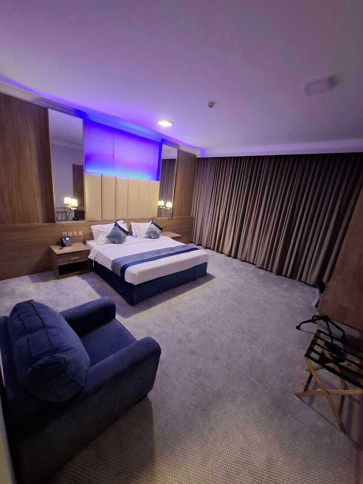 Ein Hotelzimmer mit einem großen Bett, einer Sitzecke, einem Schreibtisch und einem Spiegel.