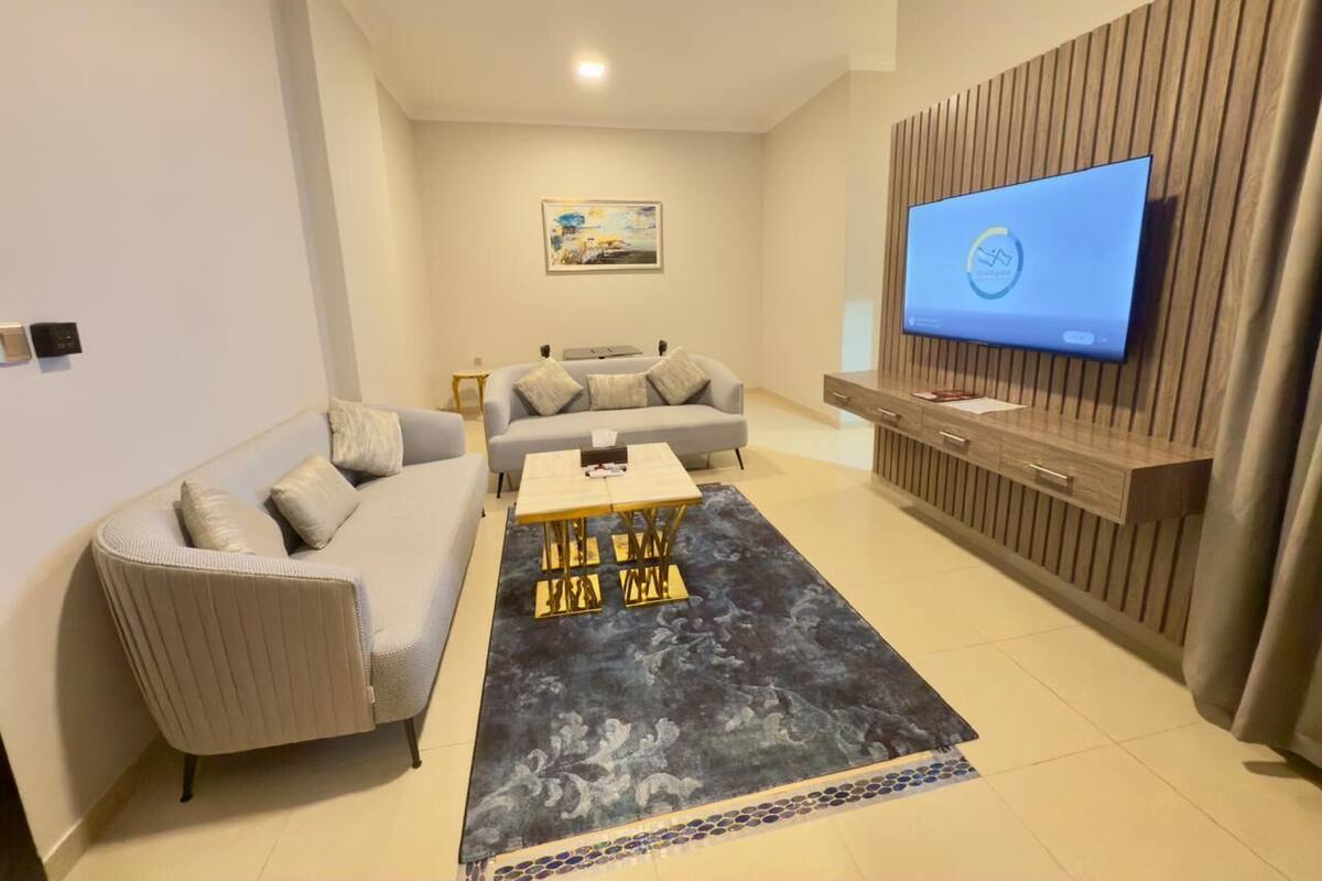 Un salon moderne avec un canapé, une table basse et un téléviseur à écran plat fixé à un mur en bois.