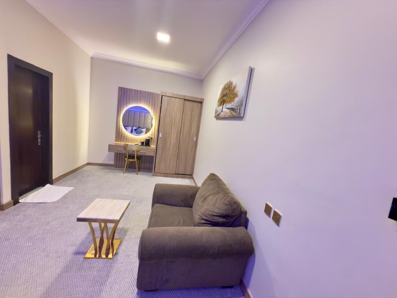 A modern living room with a sofa, a small table, a round mirror, and a wardrobe.