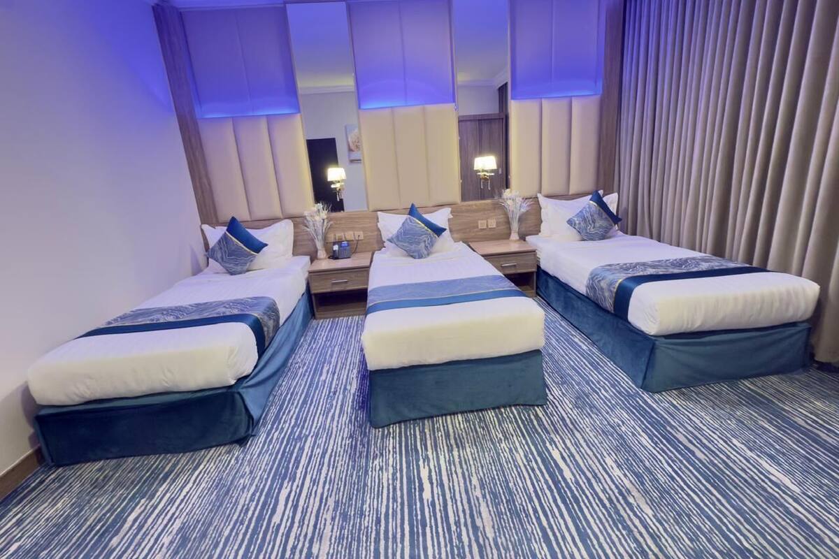 Une chambre d’hôtel avec deux lits, un grand miroir et une moquette à rayures bleues.