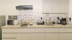 A kitchen with a microwave, toaster, coffee maker, and a sink.