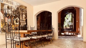 A dining area with a long table, chairs, and a mural on the wall. - Paseo Colonial - Sabbatical 1 (Santo Domingo)