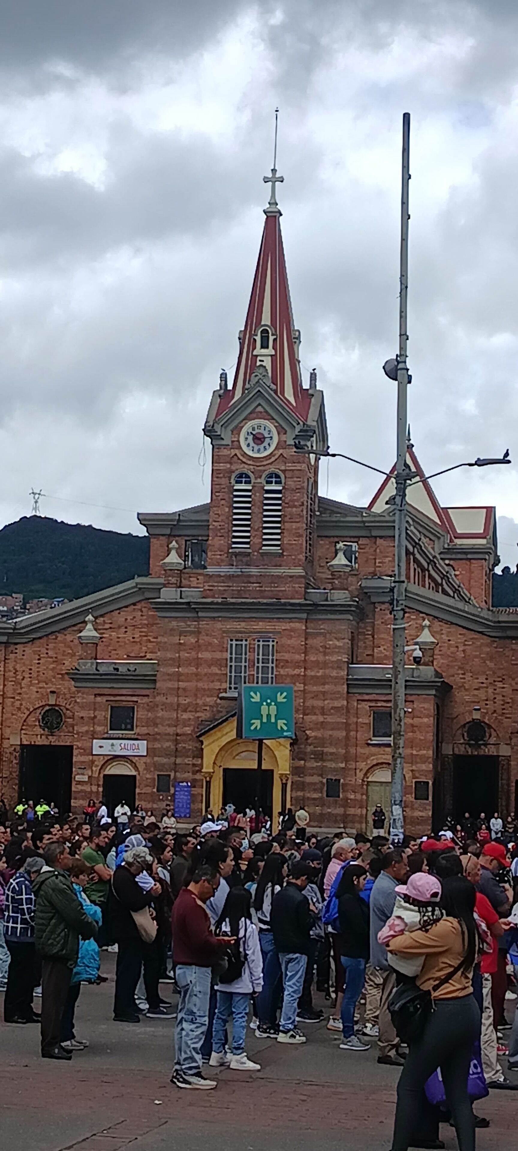 Un edificio histórico con una torre de reloj, un cartel que dice 'SALIDA' y una multitud de personas en primer plano.