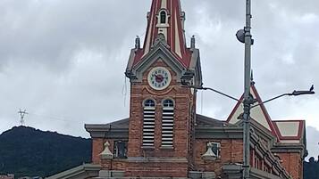 Un edificio histórico con una torre de reloj, un cartel que dice 'SALIDA' y una multitud de personas en primer plano.