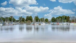 Ein Yachthafen mit vertäuten Booten, ruhigem Wasser und Bäumen im Hintergrund.