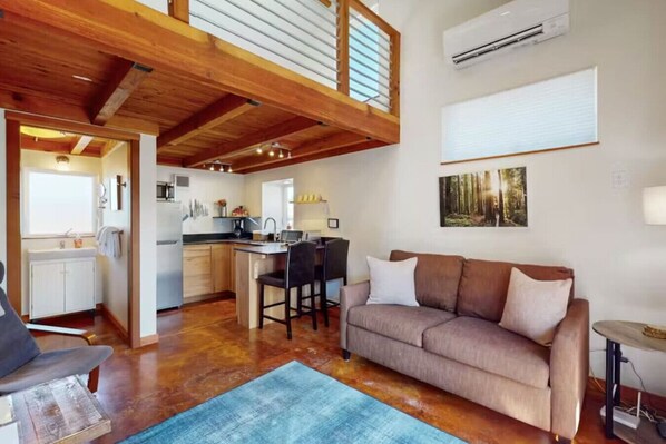 A cozy living area with a sofa, a coffee table, and a kitchen in the background.