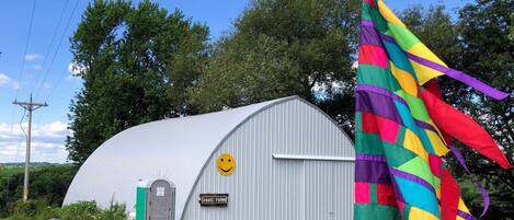 A metal barn with a green door and a sign that reads "PAVIC FARM".