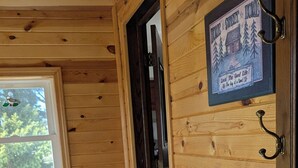 Een houten interieur met een deur waarop een ‘Home Sweet Home’ bordje staat, een raam met een vogelstickertje en een bloempot op een houten tafel.