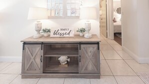 Una consola de madera con un cartel que dice 'SIMPLY blessed', dos lámparas y una escultura de pez.