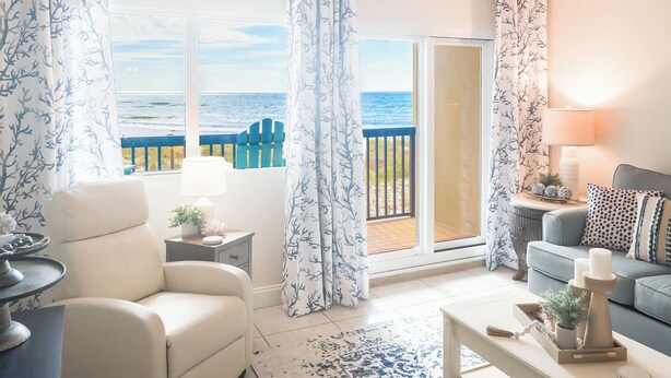 Una sala de estar con vista al mar, un sofá, una mesa de centro y una lámpara.