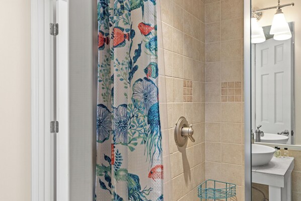 A bathroom with a shower curtain featuring a floral pattern, a sink with a mirror, and a towel rack.