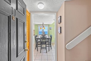 Un couloir menant à une salle à manger avec vue sur l’océan, agrémentée d’un lustre et d’une porte sur laquelle est apposé un panneau « interdiction de fumer ».