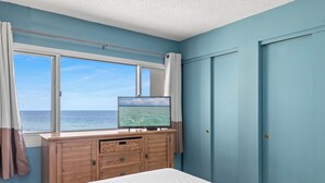 A bedroom with a large window, a wooden dresser, and a bed. - Pinnacle Port, B2-307 (Panama City Beach)
