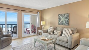 A living room with a sofa, a coffee table, and a view of the ocean through large sliding glass doors. - Pinnacle Port, B2-307 (Panama City Beach)