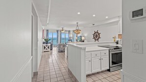A modern kitchen with white cabinetry, a central island, and a view to the outside. - Pinnacle Port, B3-405 (Panama City Beach)