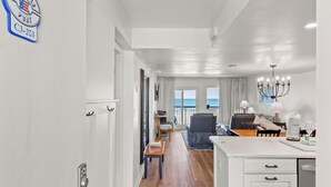 A modern hotel room with a view of the ocean, a dining area, and a kitchen.
