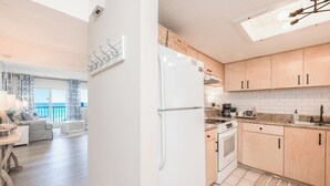 Eine moderne Küche mit Holzausstattung, einem weißen Kühlschrank und einer Essecke mit Blick.