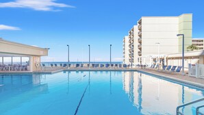 A swimming pool with lounge chairs and a building with balconies. - Pinnacle Port, C3-604 (Panama City Beach)