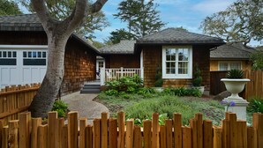A two-story house with a wooden exterior, a front porch, and a fenced backyard.